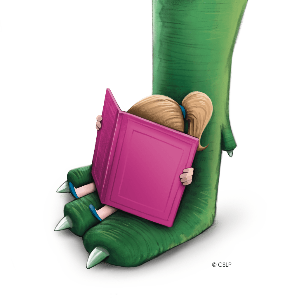 A small child with a ponytail lounges on a dinosaur's foot while reading a big book
